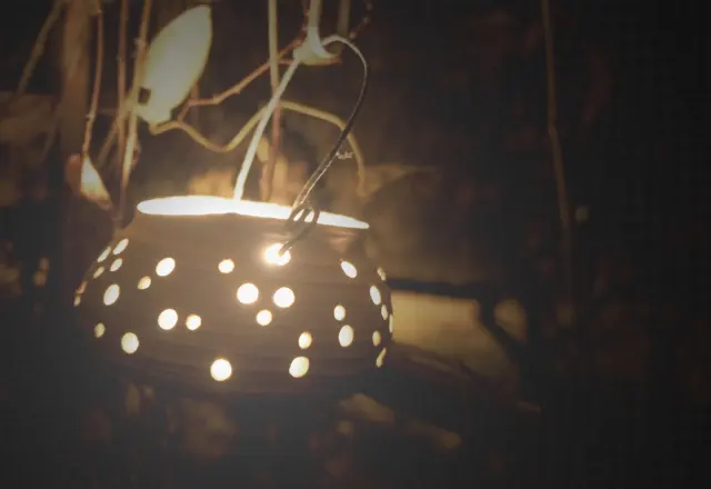 A candle pot glowing in the garden at dusk