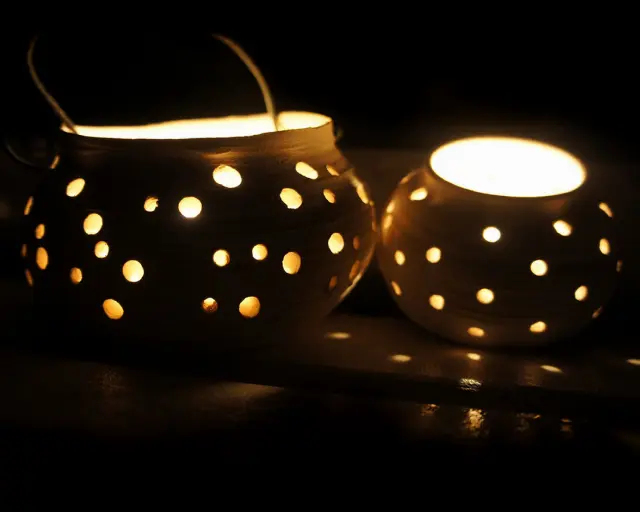 Two lit candle pots in the dark