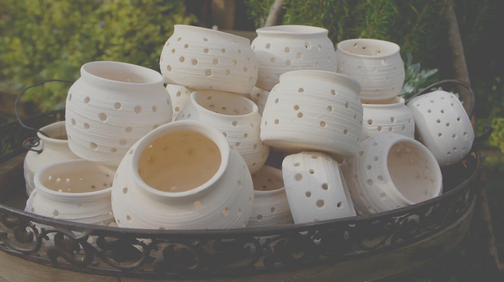 White pots with holes on a wrought-iron tray